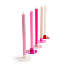 Set of colorful candles on stands against a white background