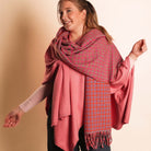Woman wearing a pink and red patterned scarf against a beige background