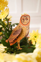 Decorative owl figurine among yellow flowers