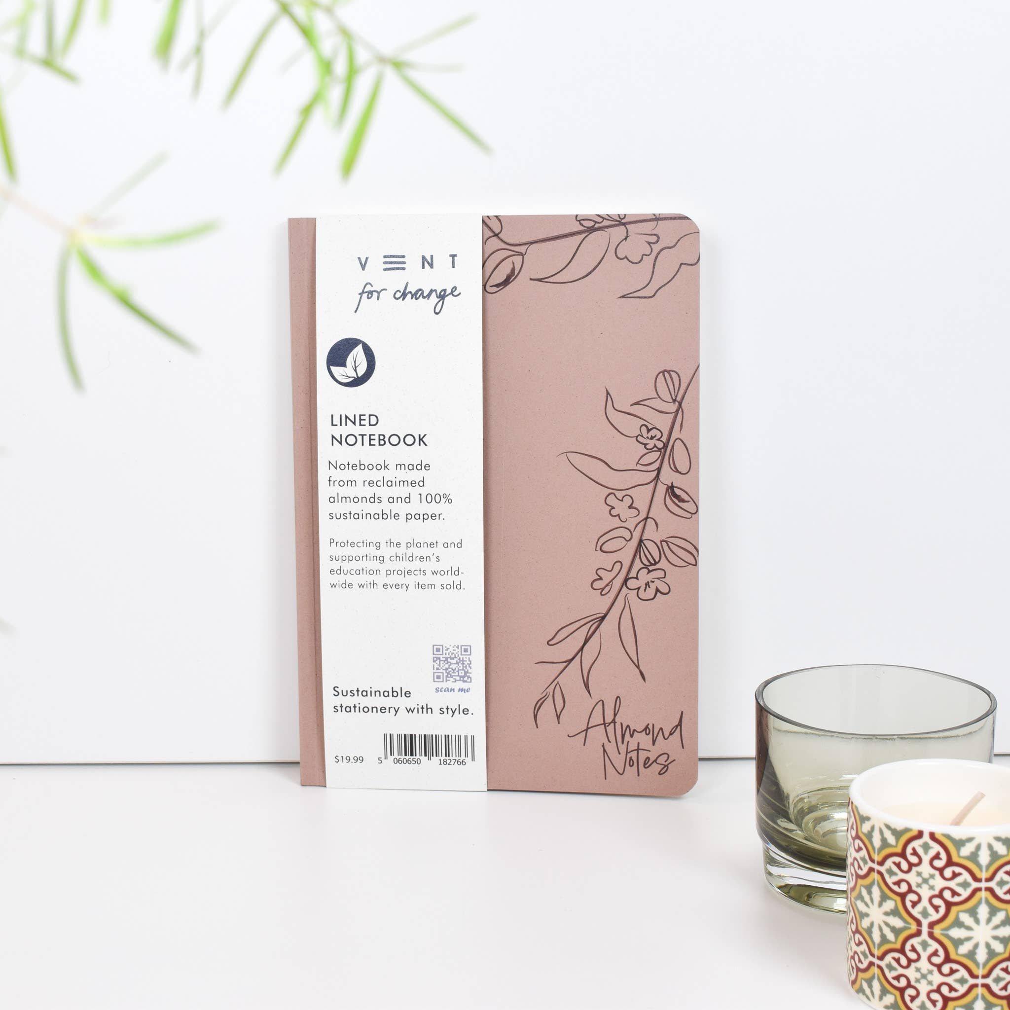 Sustainable notebook packaging with a plant and candle on a white background