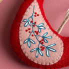 Felt ornament with embroidered design on a pink background