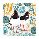 Illustration of two black and white birds with red beaks surrounded by marine plants on a white background.