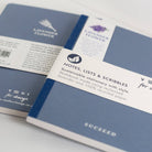 Two blue notebooks with labels on a light gray background