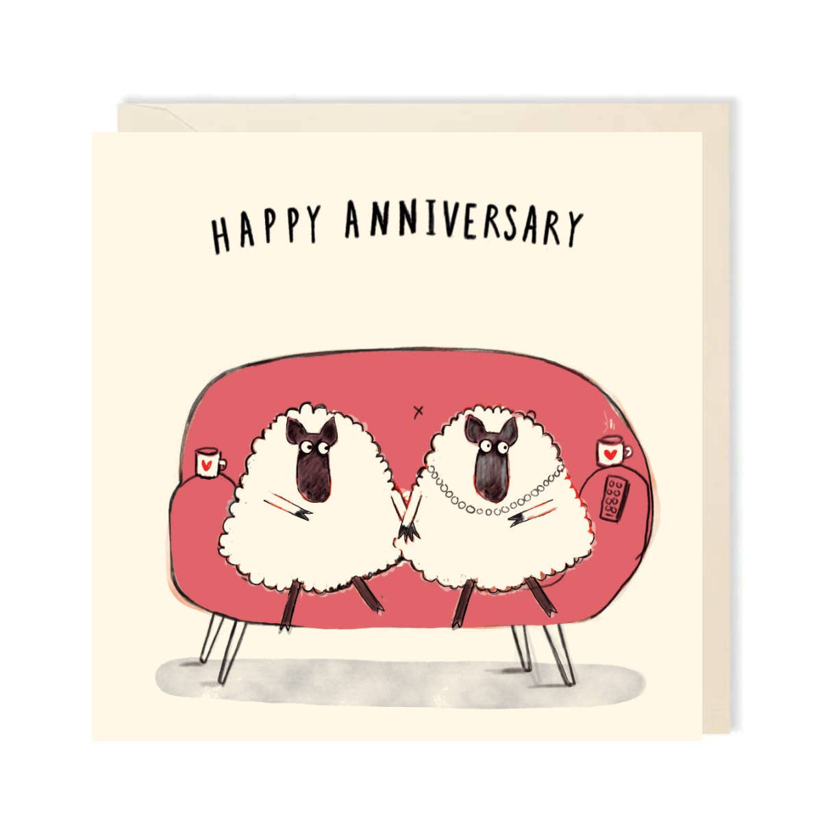 A square greeting card with a cream background featuring the text 'HAPPY ANNIVERSARY' above an illustration of two sheep sitting on a pink couch, with a matching cream envelope behind it.