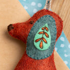 Felted ornament with embroidered design held against a light blue background