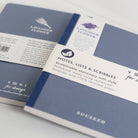 Two blue notebooks with labels on a light gray background