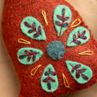 Red fabric with embroidered green leaves and yellow accents