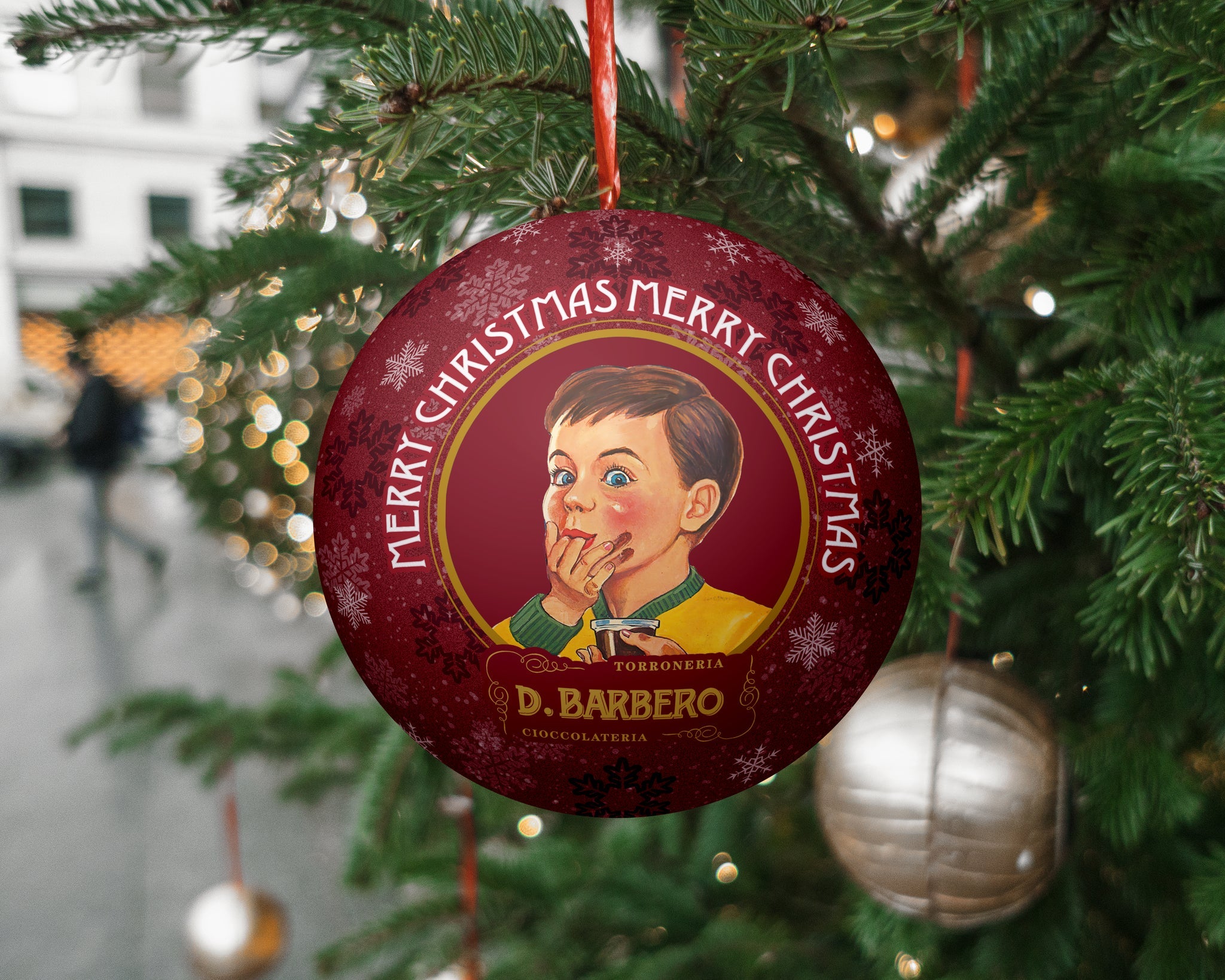 Decorative Christmas ornament with a vintage design of a boy and 'Merry Christmas' text, hanging on a tree.