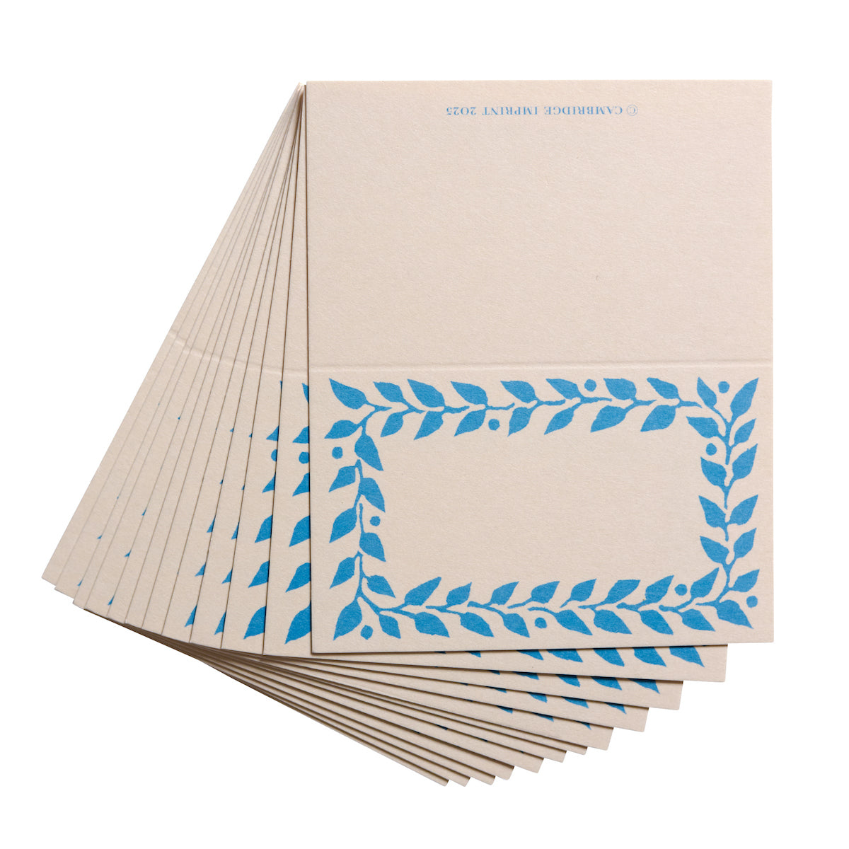 Stack of beige notebooks with blue leaf patterns on a white background
