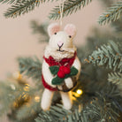 Felt mouse ornament with a red scarf and holly berry hanging on a Christmas tree.