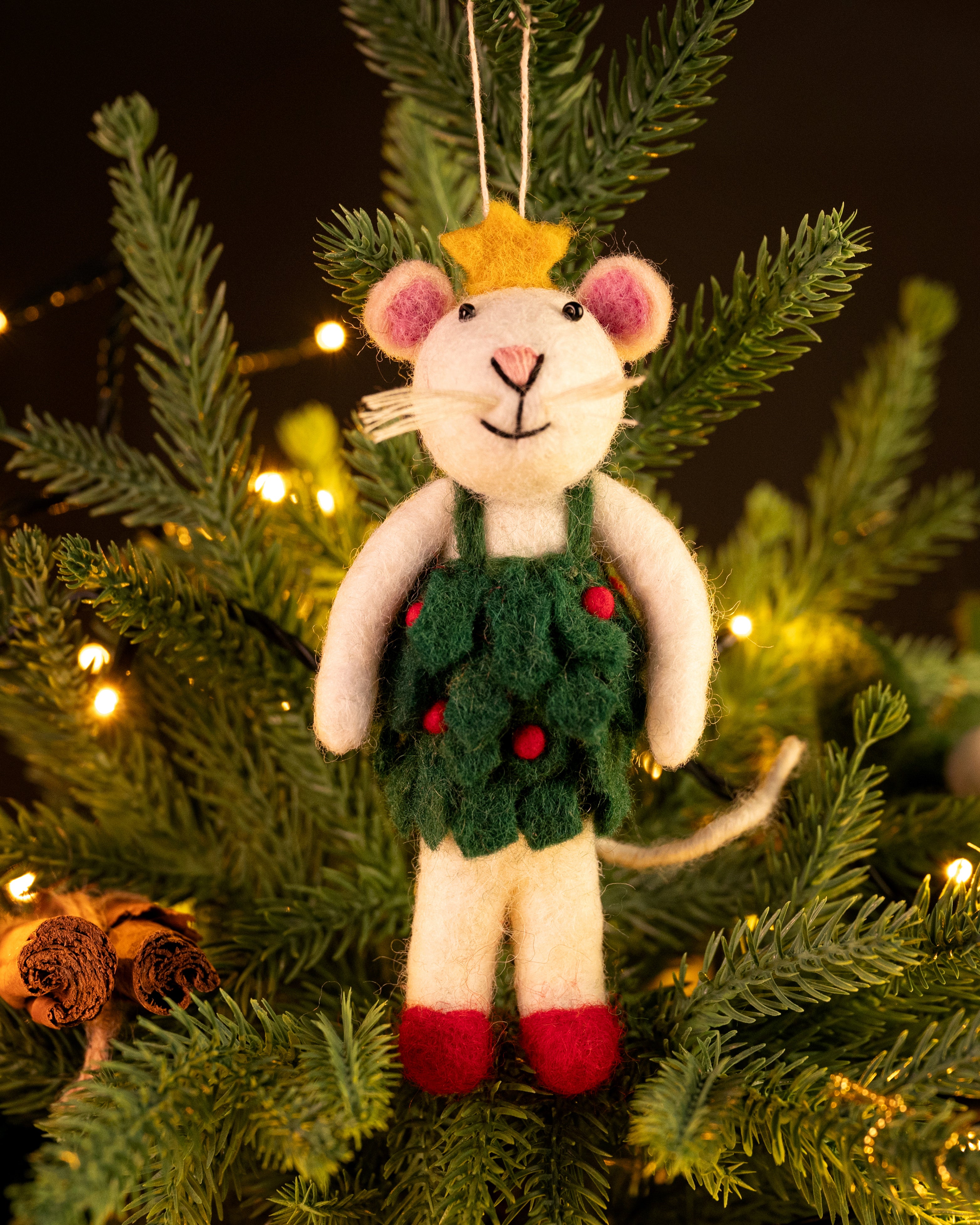 Decorative mouse ornament in a green sweater hanging on a Christmas tree.