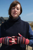 Woman wearing a dark blue sweater and colorful patterned gloves outdoors.