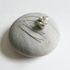 Silver earrings on a gray stone with a white background