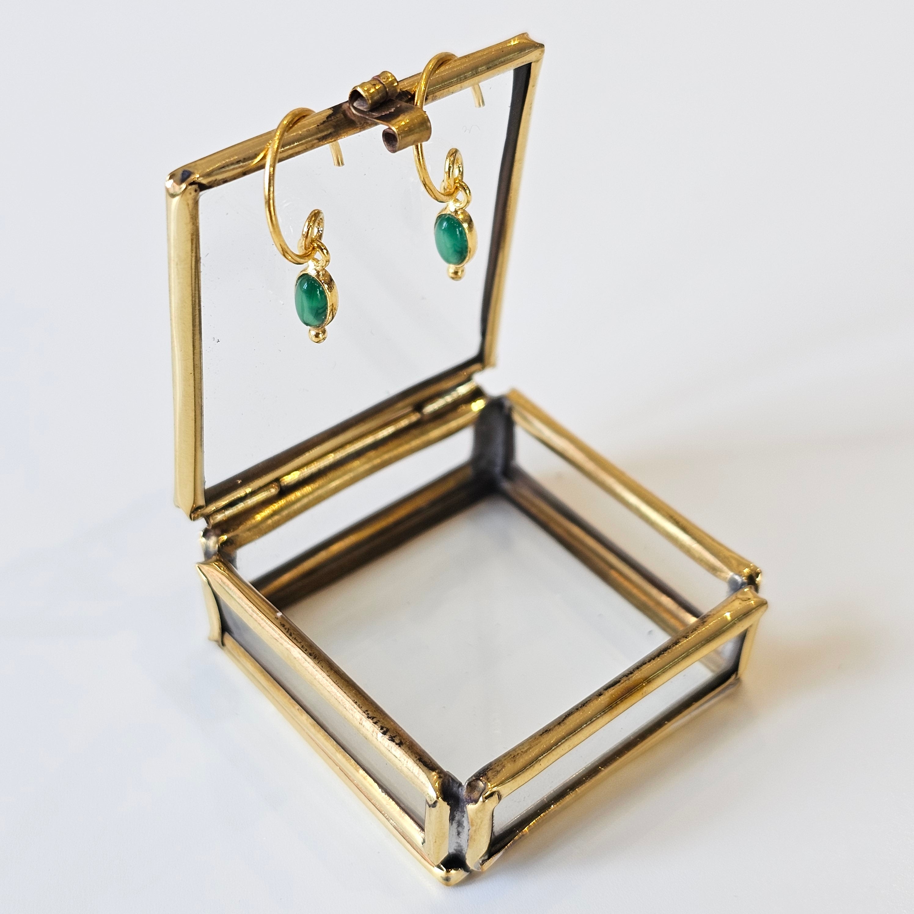 Gold jewellery box with green agate earrings on a white background