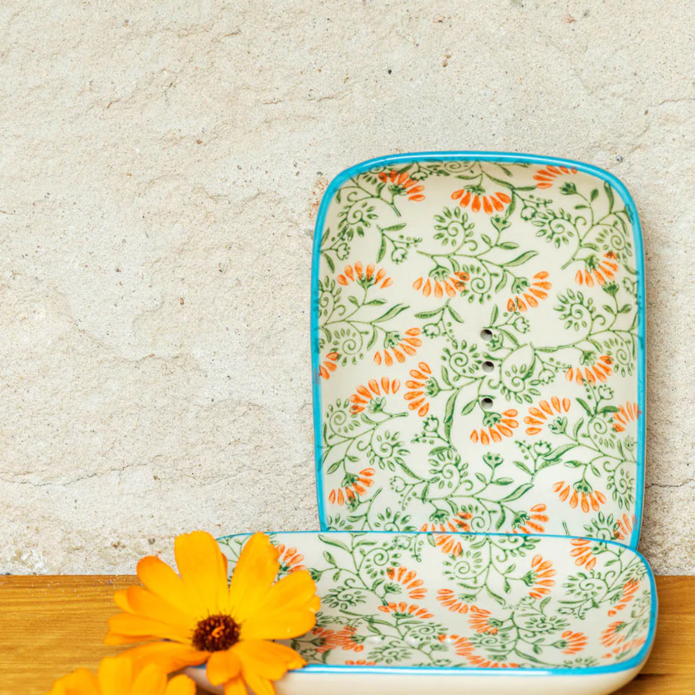 Floral-patterned soap dish on a wooden surface with yellow flowers.