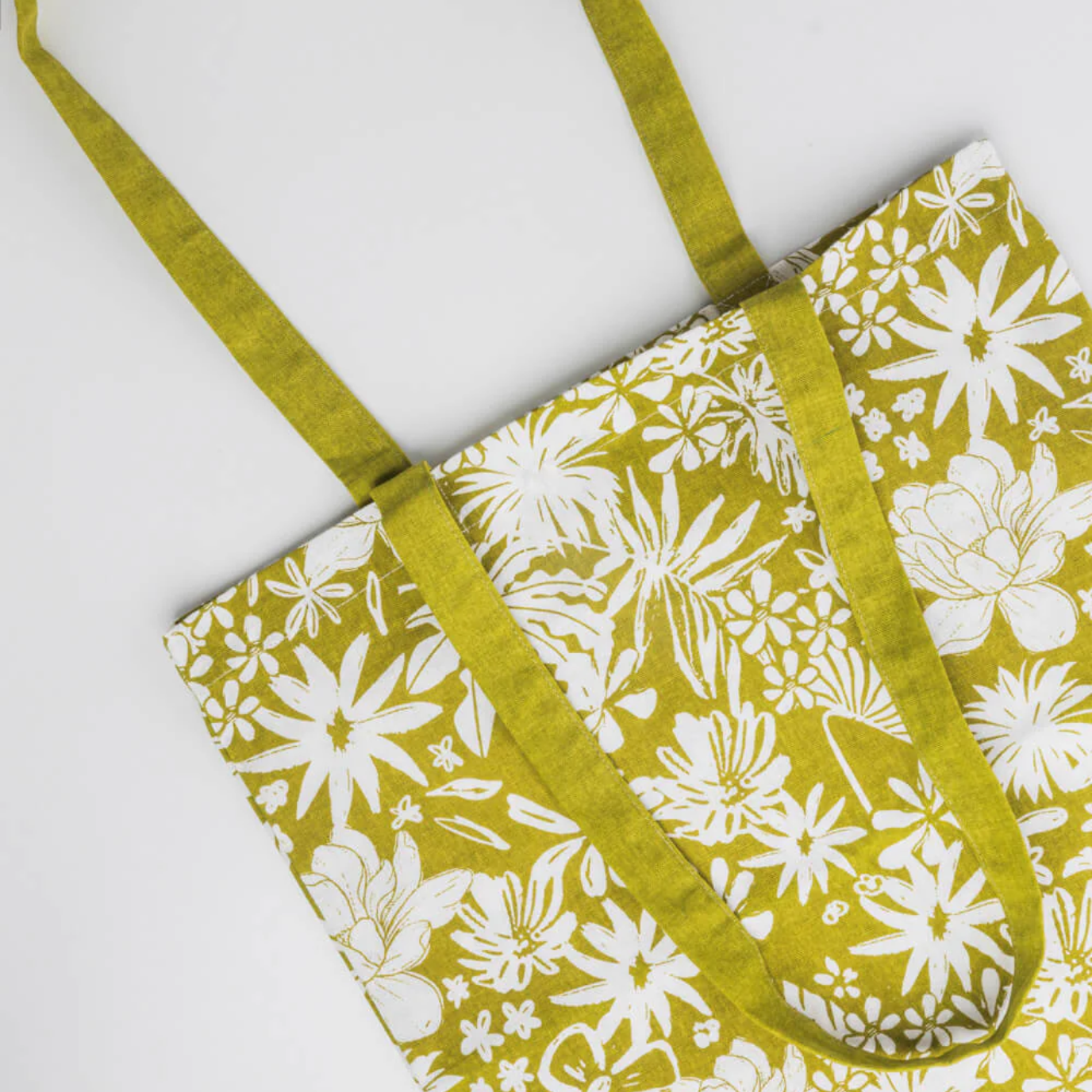 Floral-patterned bag with green strap on a white background