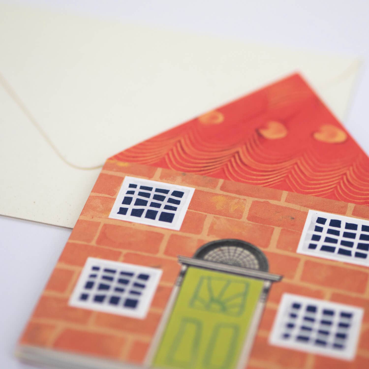 Card with a house design featuring a green door and orange walls on a white background