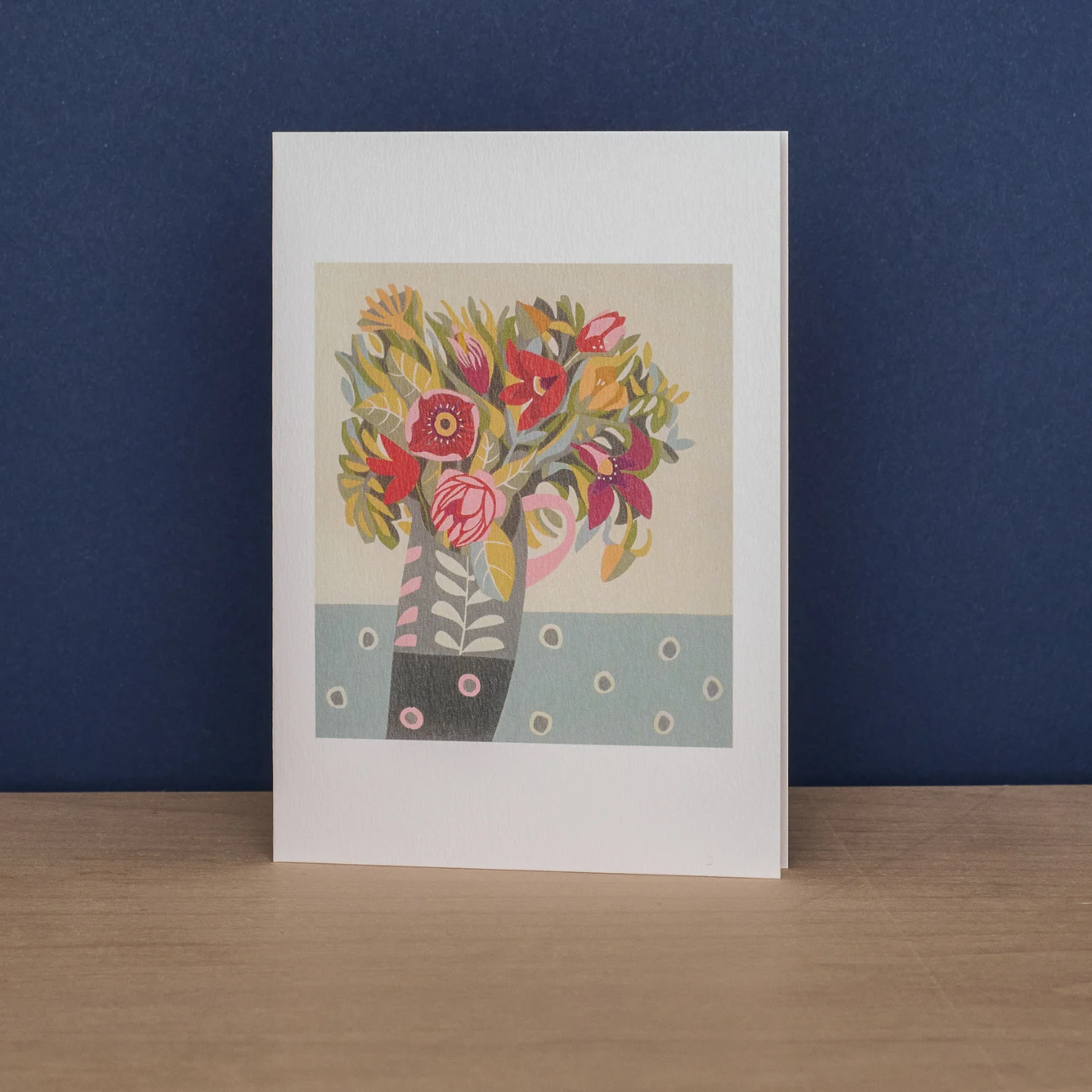 Greeting card with artwork by Jane Walker of red, pink and gold-toned flowers in a grey and pink vase.