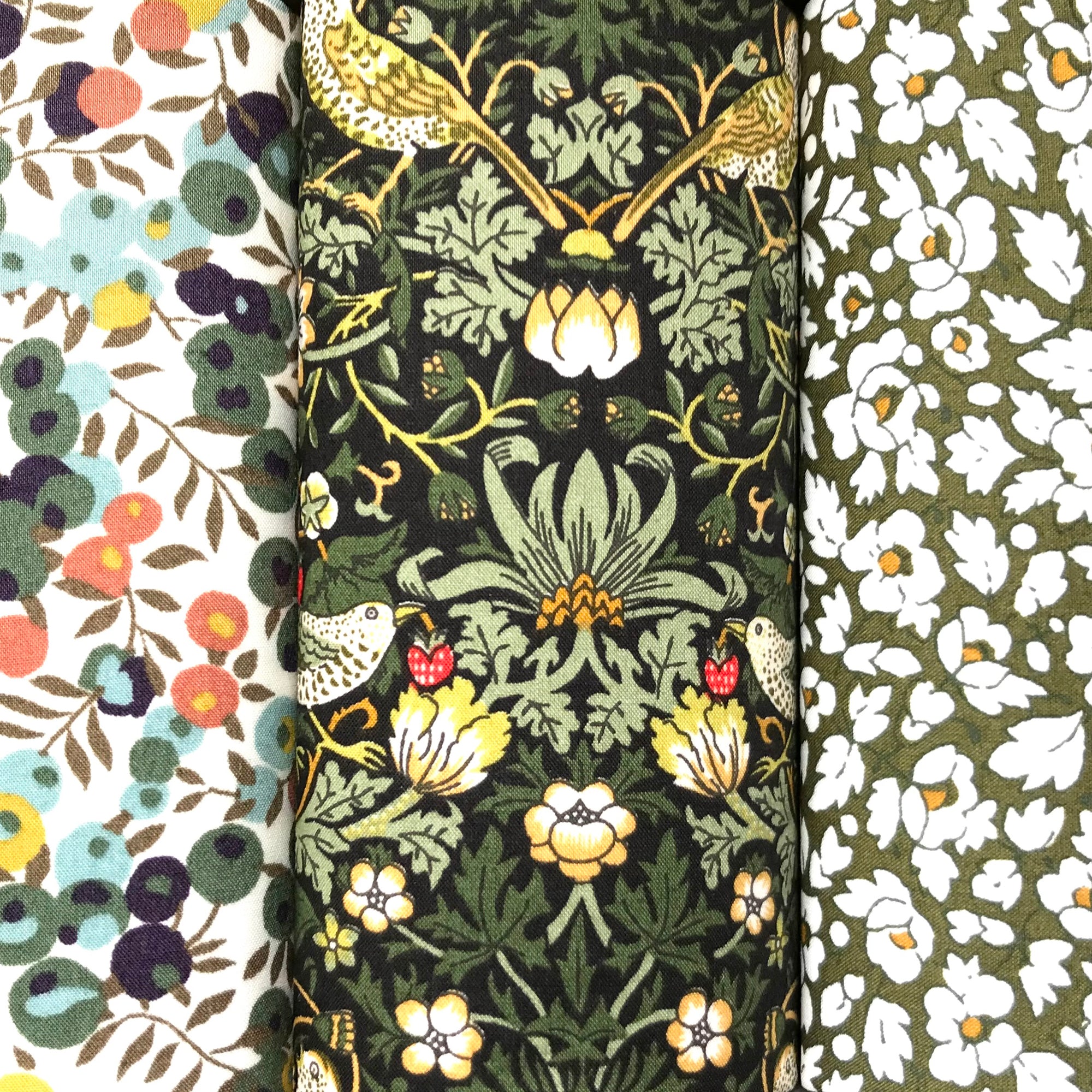 Three floral fabric patterns in green Liberty cotton side by side.