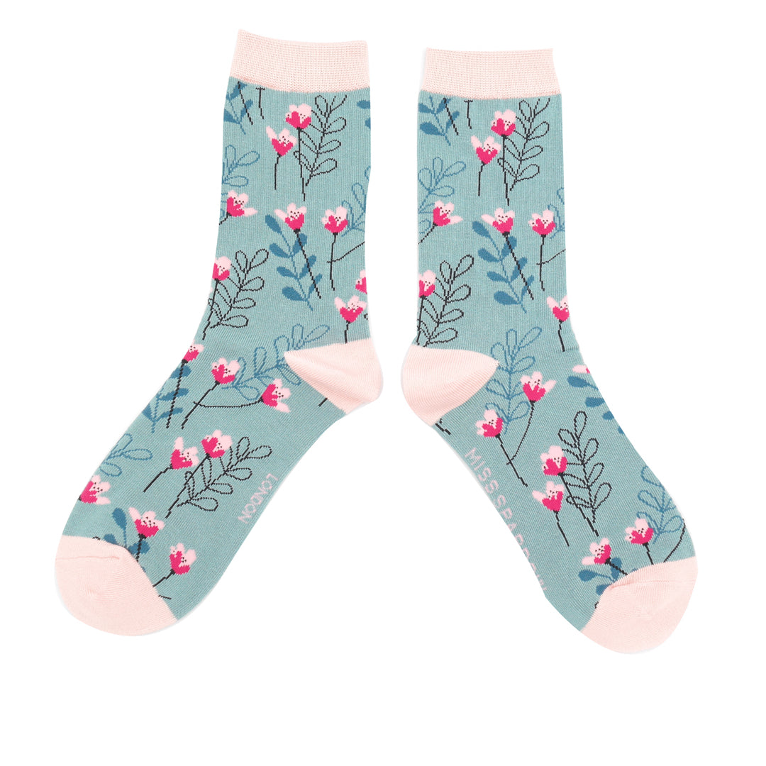 Floral patterned socks with pink accents on a light blue background