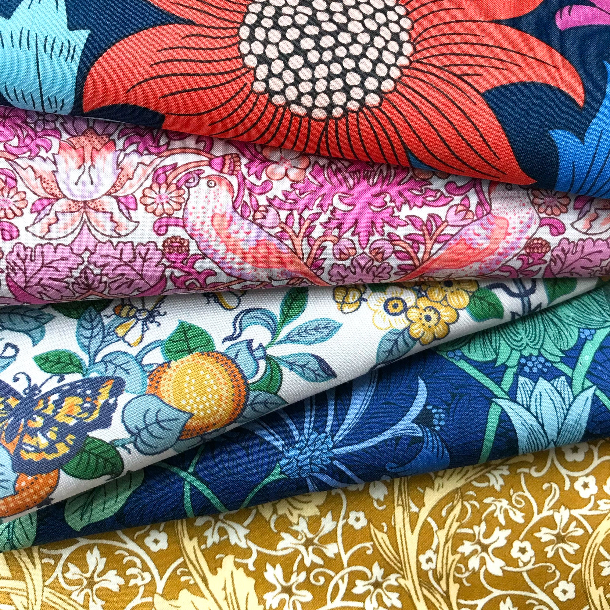 Stack of colourful floral and nature-themed fabrics