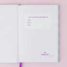 Open notebook with purple text on a pink background