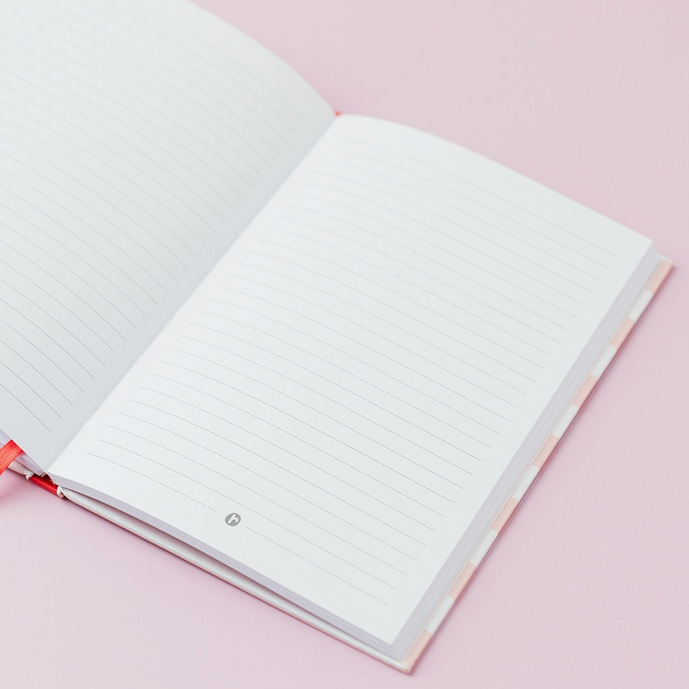 Open notebook with lined pages on a pink background