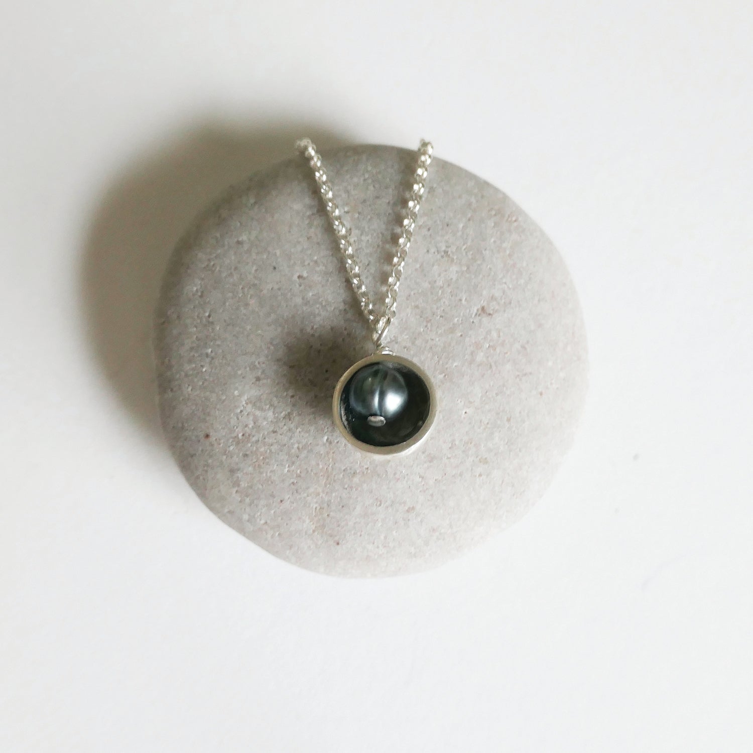 Necklace with a black pendant on a light gray stone surface