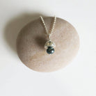 Necklace with a black pearl pendant on a stone surface