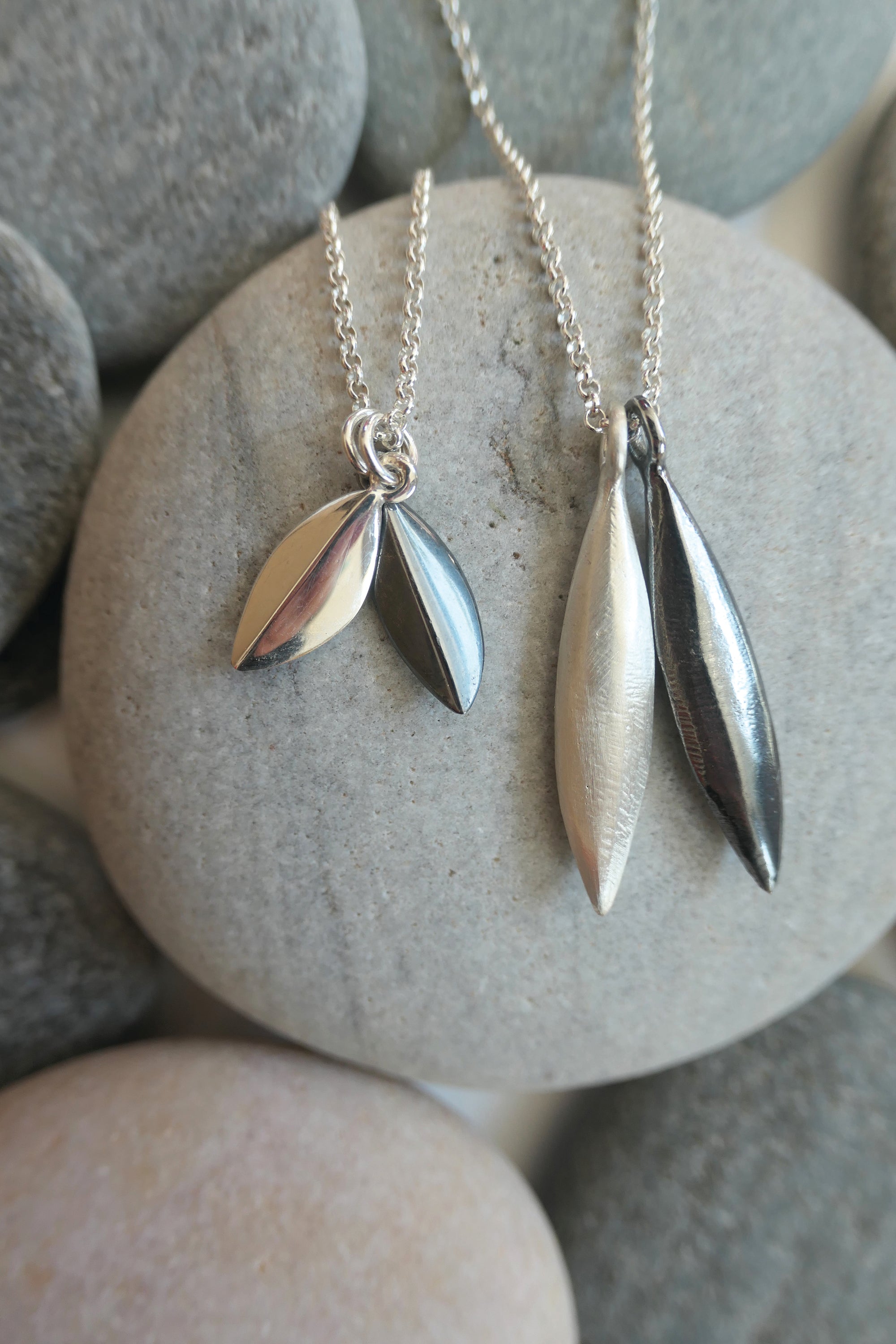Silver seed shaped pendants on a stone surface