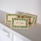 Three beige cards with green leaf patterns on a white surface