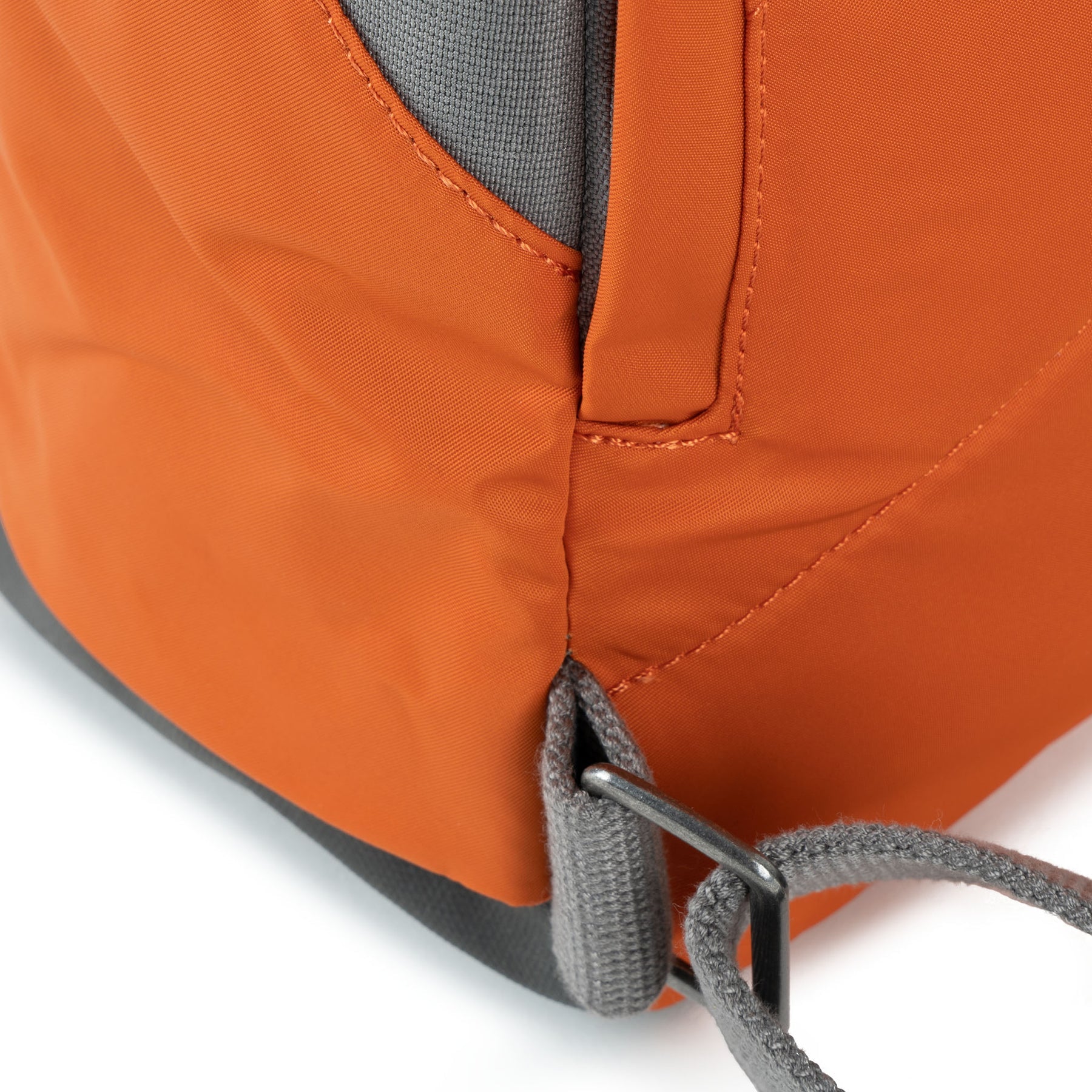 Close-up of an orange backpack with gray straps on a white background