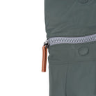 Close-up of a green jacket with a zipper and brown pull tab on a white background