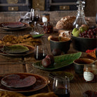 Wooden table set with ceramic plates, glasses, and food items in a rustic setting.