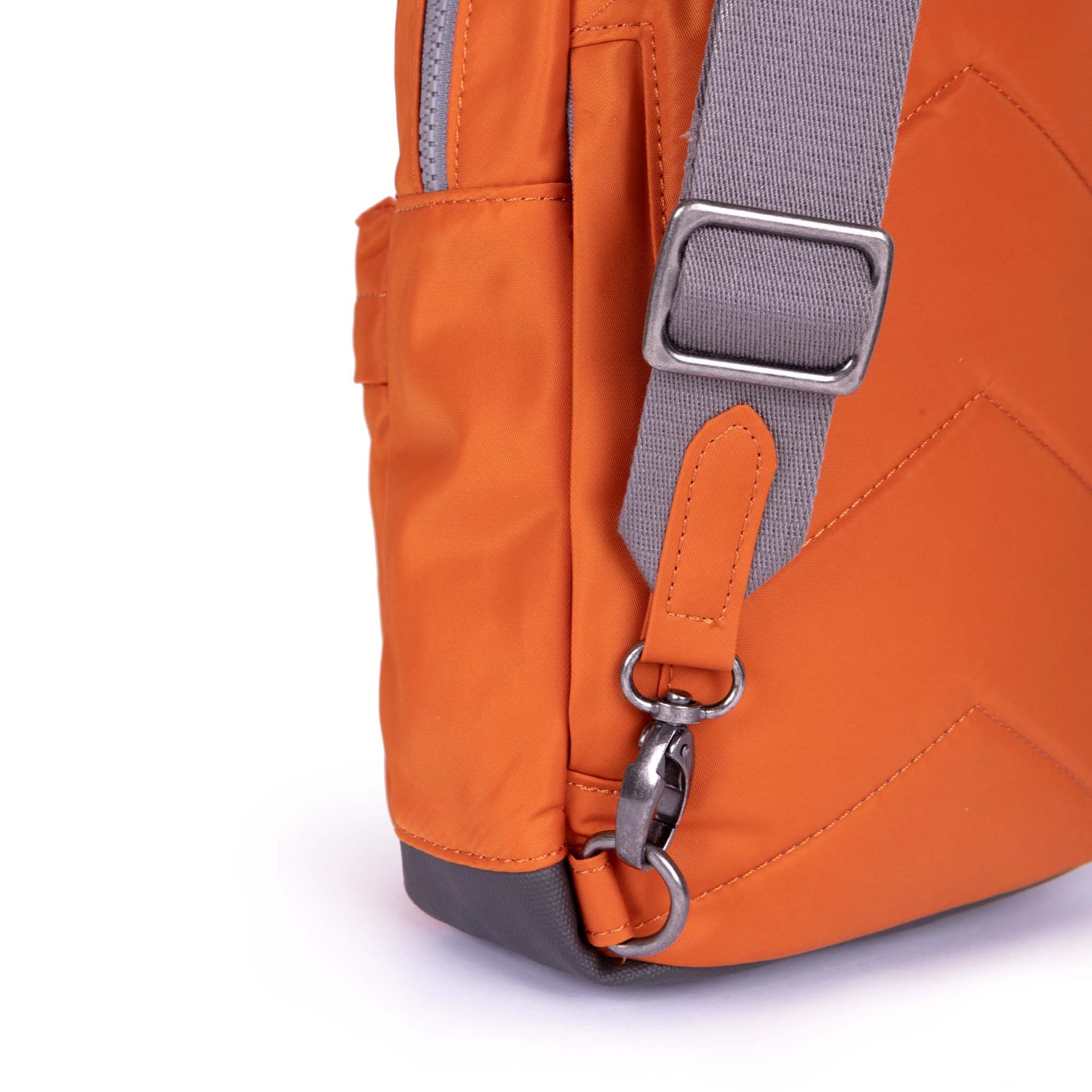 Close-up of an orange backpack with a gray strap on a white background