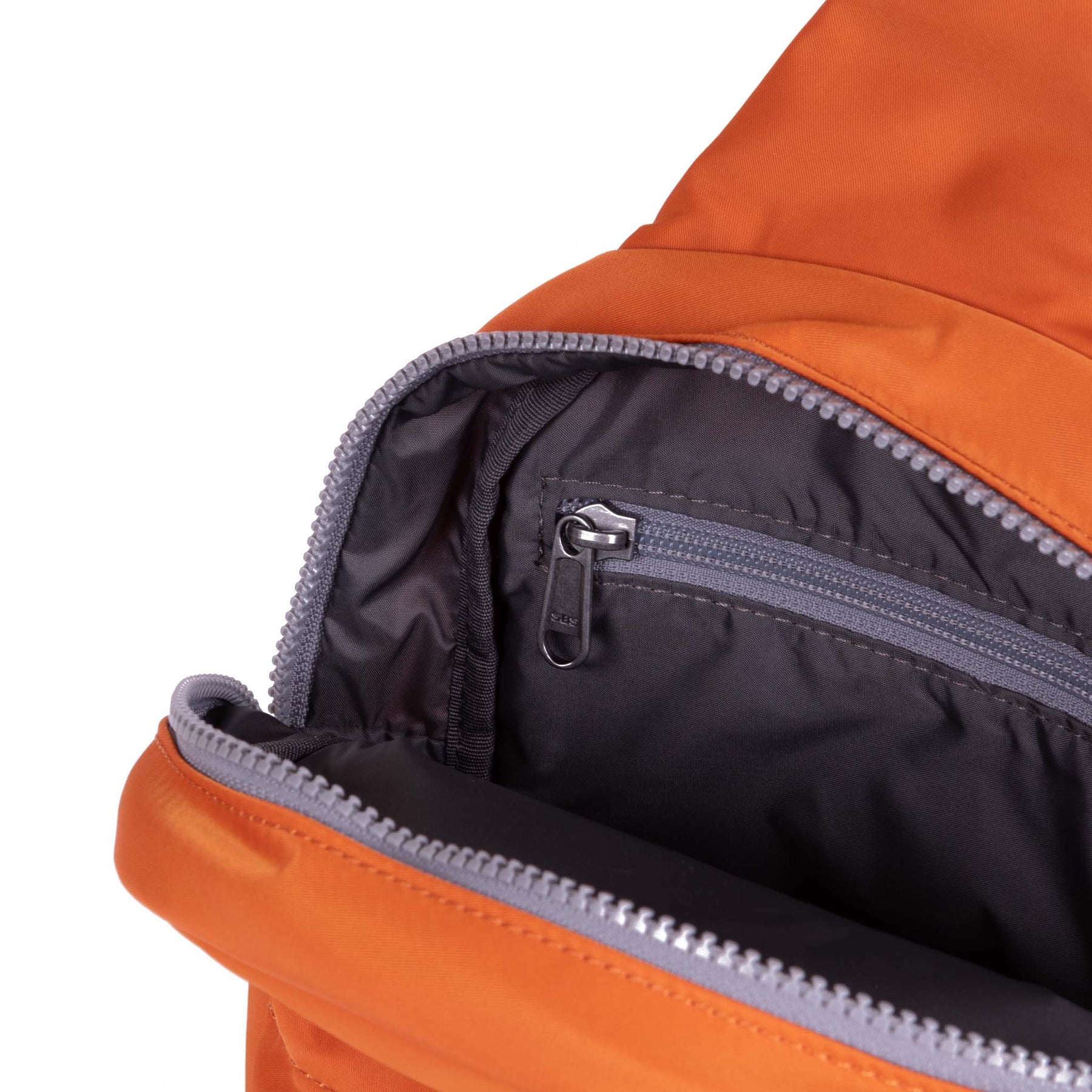 Close-up of an orange backpack with a zipper on a white background