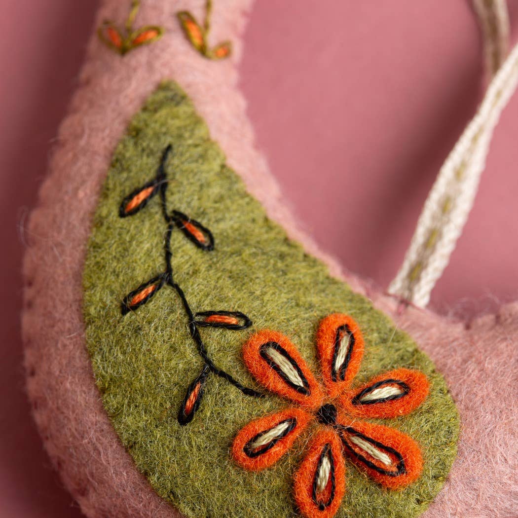 Felted ornament with embroidered orange flower on a pink background