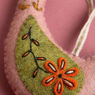 Felted ornament with embroidered orange flower on a pink background