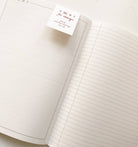 Open notebook with lined pages and a visible brand label on a white background