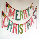 Colorful 'Merry Christmas' banner hanging on a white wall