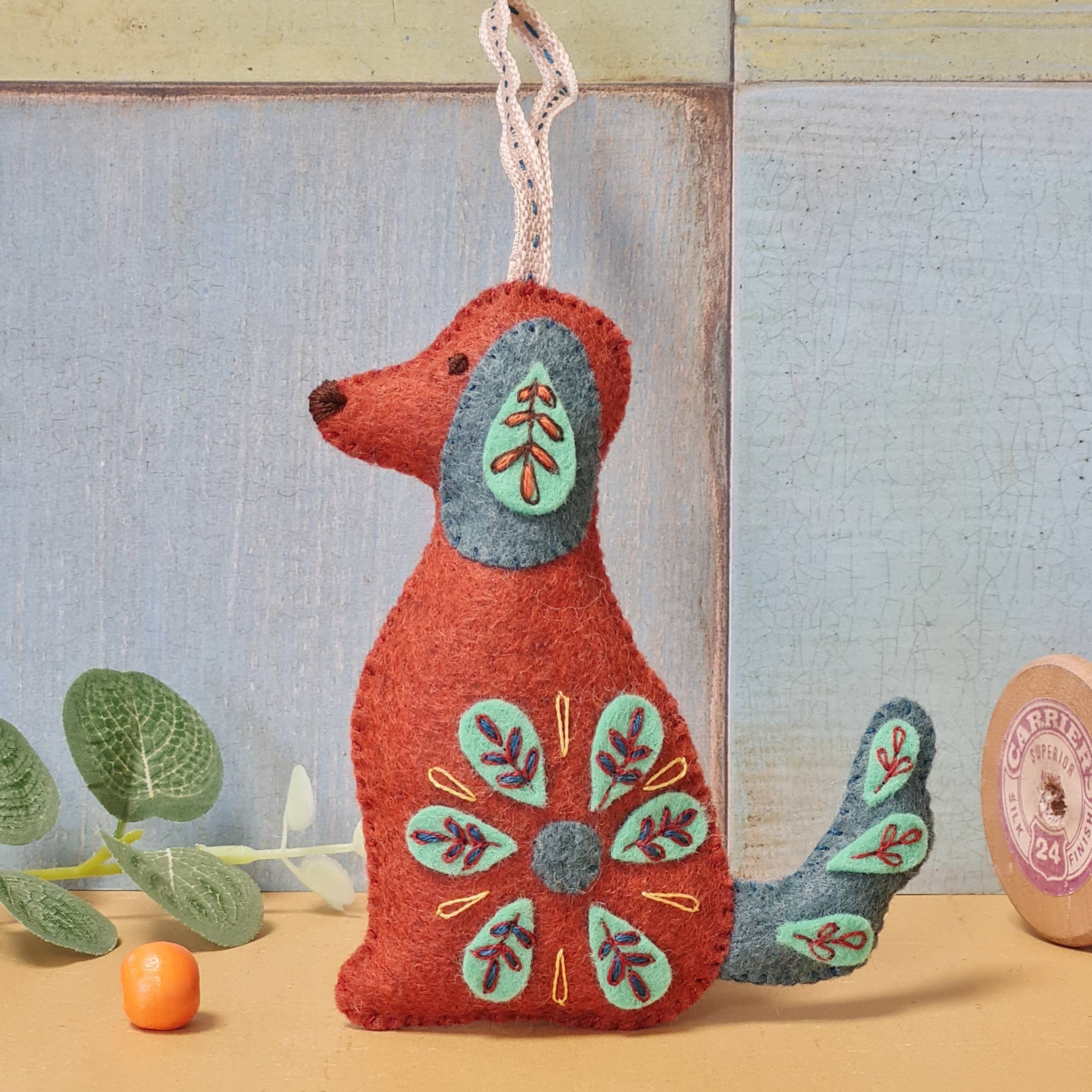 Decorative dog ornament with floral patterns on a wooden surface and textured wall background