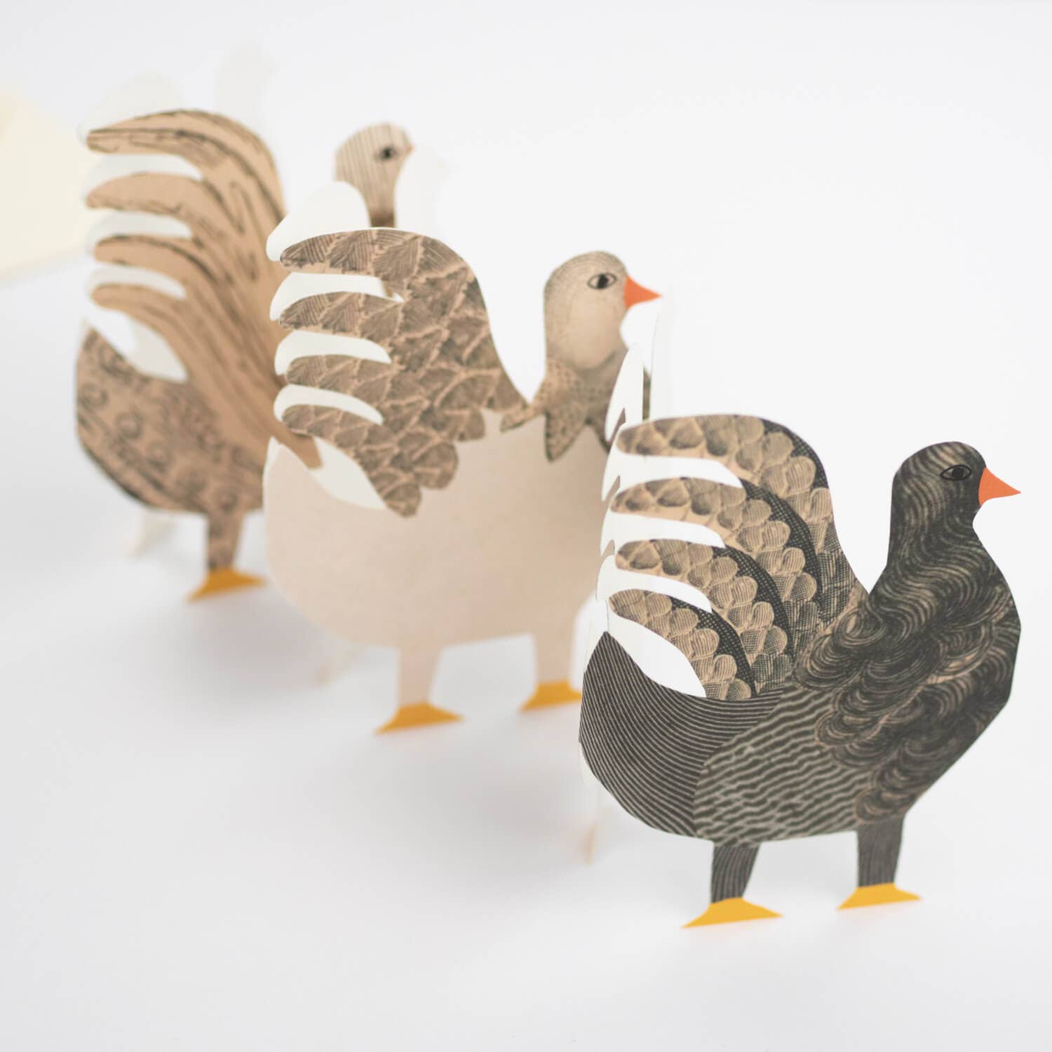Three paper goose figures on a white background