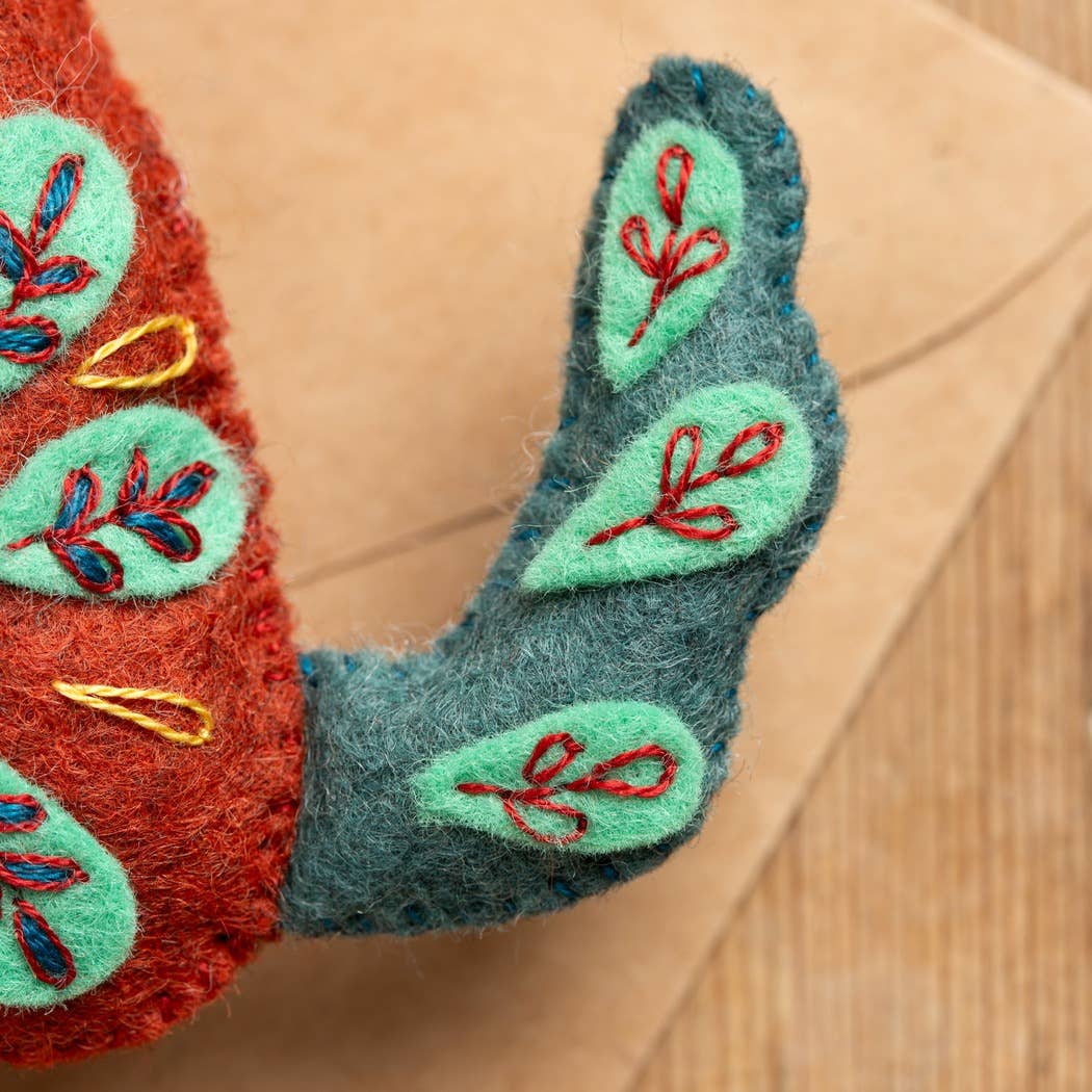 Decorative felt item with embroidered details on a wooden surface