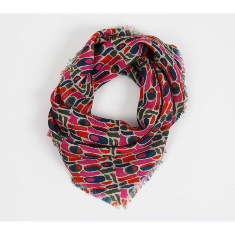 A lightweight scarf with a colorful abstract geometric pattern, featuring pink, red, navy, and olive green shapes on a cream background with fringed edges, shown on a plain white background.