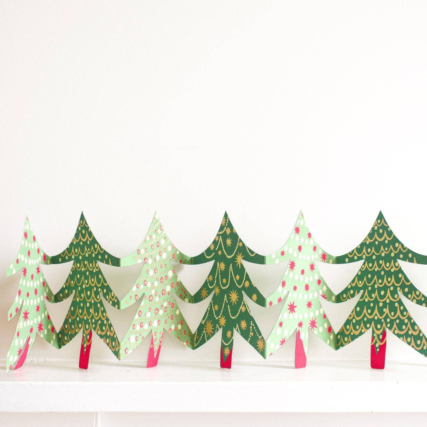 Decorative paper Christmas trees with green, red, and white patterns on a white background