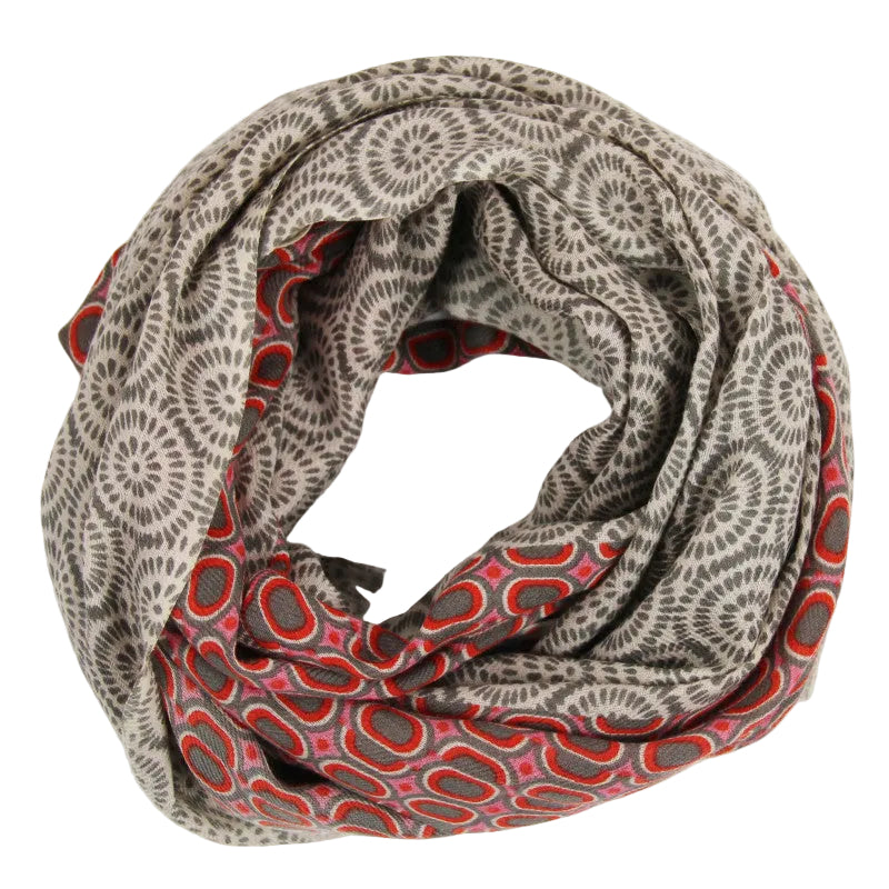 A lightweight infinity scarf with a dual-pattern design, featuring a gray and beige sunburst motif on one side and a red, pink, and gray oval pattern on the reverse, displayed on a clean white background.