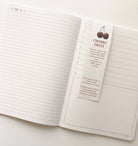 Open notebook with a cherry fruit-themed page marker on a white background