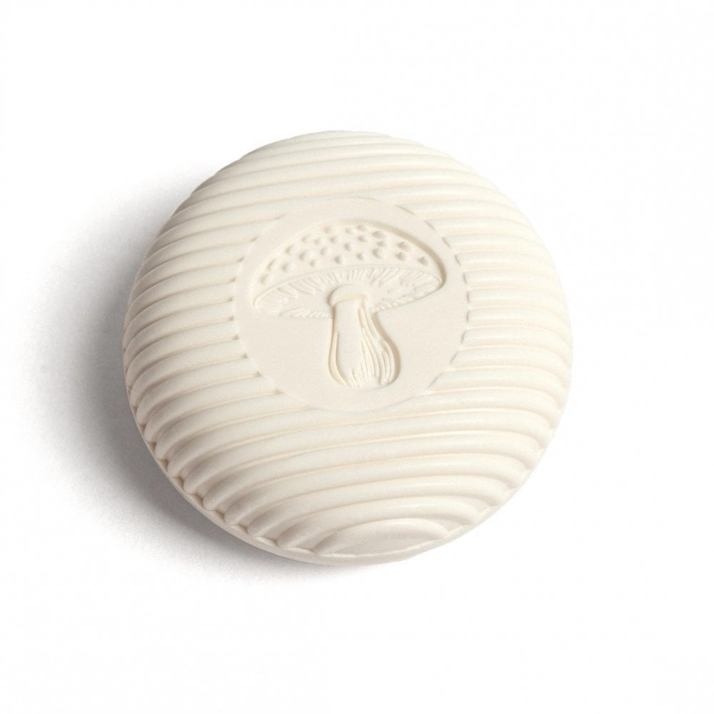 Round white ceramic object with a mushroom design on a white background