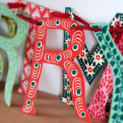 Colorful paper letter 'R' with decorative patterns on a wooden surface.