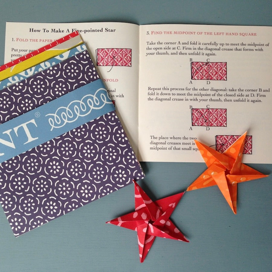 Patterned paper sheets with origami stars and a book on origami instructions.